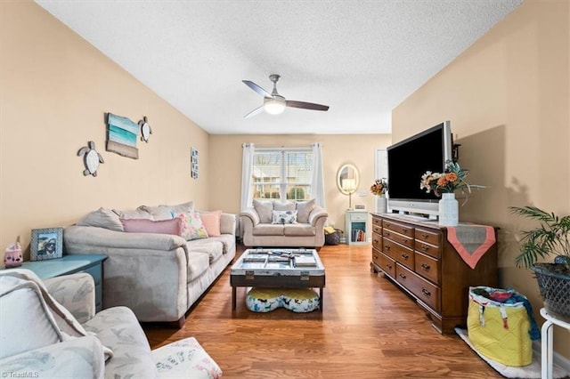 living room featuring ceiling fan, hardwood / wood-style floors, and a textured ceiling