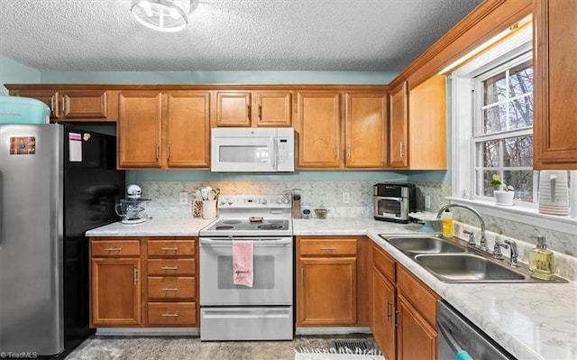 kitchen featuring a textured ceiling, stainless steel appliances, a wealth of natural light, and sink