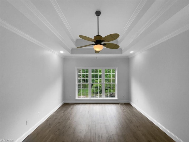 unfurnished room featuring a tray ceiling, dark wood-type flooring, ceiling fan, baseboards, and crown molding