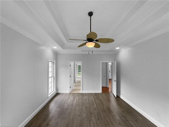 unfurnished bedroom with a tray ceiling, dark wood finished floors, crown molding, baseboards, and recessed lighting