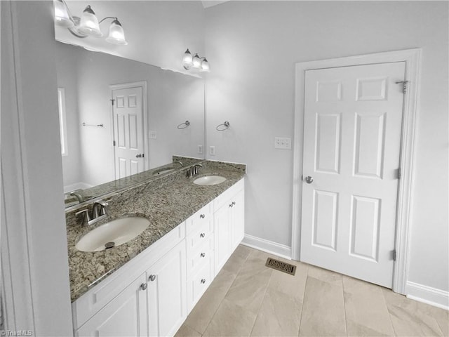 bathroom featuring baseboards and double vanity