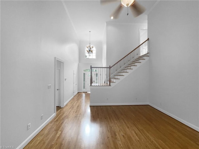 entrance foyer with stairs, wood finished floors, a chandelier, baseboards, and ceiling fan