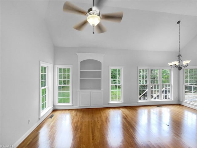 unfurnished living room featuring wood finished floors, a chandelier, a ceiling fan, baseboards, and high vaulted ceiling