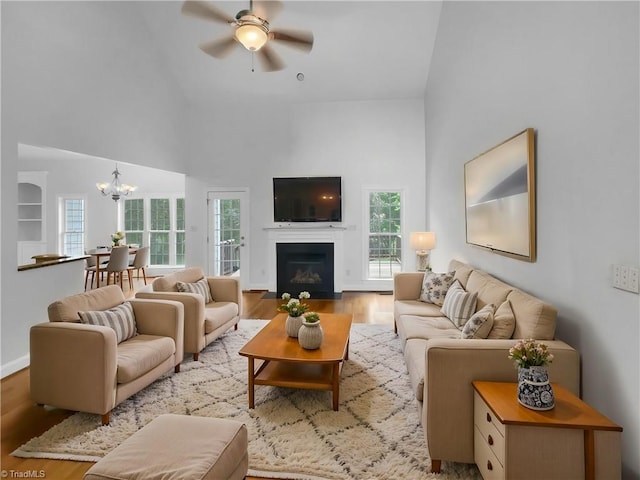 living area featuring high vaulted ceiling, a chandelier, ceiling fan, plenty of natural light, and wood finished floors