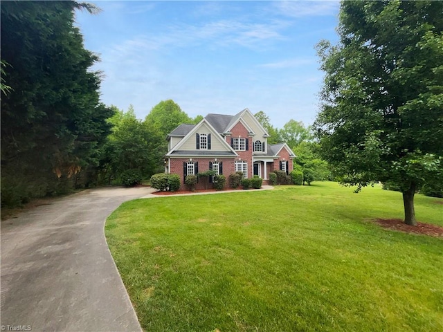 view of front of house with concrete driveway, a front yard, and brick siding