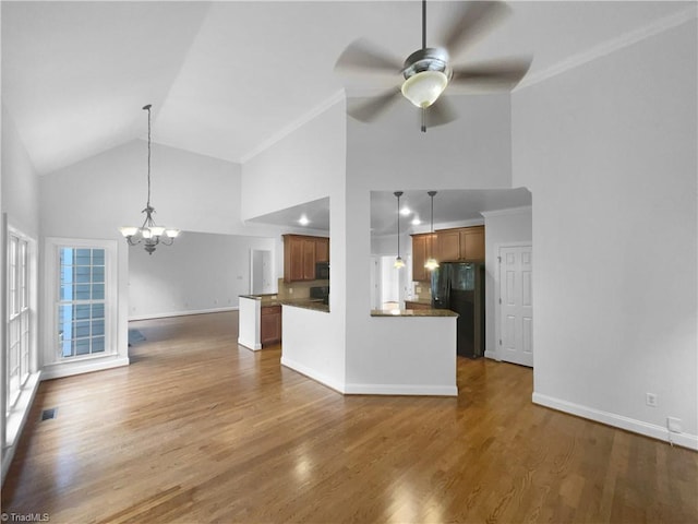 unfurnished living room featuring a chandelier, high vaulted ceiling, ceiling fan, wood finished floors, and baseboards