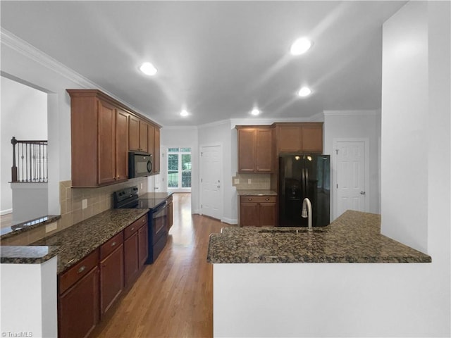 kitchen with black appliances, a peninsula, crown molding, light wood-type flooring, and recessed lighting
