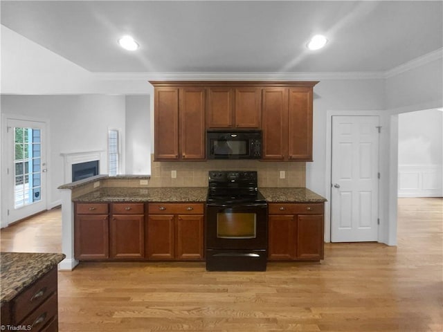 kitchen featuring black appliances, crown molding, light wood-type flooring, decorative backsplash, and dark stone countertops