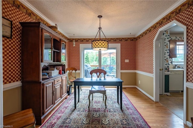 office featuring a wealth of natural light, light wood-style flooring, wallpapered walls, and a textured ceiling