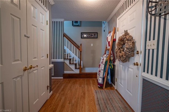 foyer featuring a textured ceiling, stairway, light wood-style floors, and baseboards
