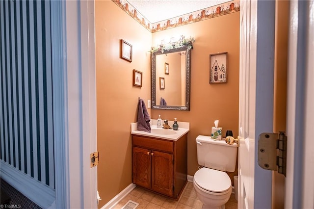 half bath with tile patterned flooring, toilet, vanity, baseboards, and visible vents