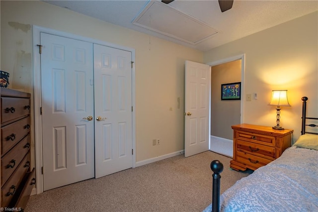 carpeted bedroom with attic access, ceiling fan, baseboards, and a closet