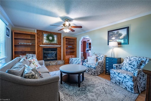 living area with ornamental molding, a textured ceiling, wood finished floors, and a fireplace