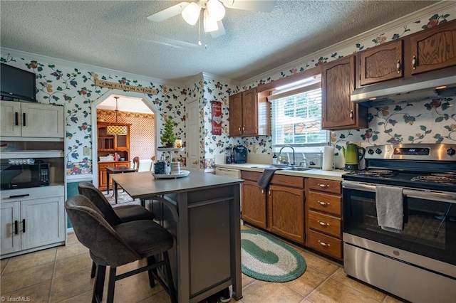 kitchen featuring under cabinet range hood, crown molding, stainless steel electric stove, a textured ceiling, and wallpapered walls