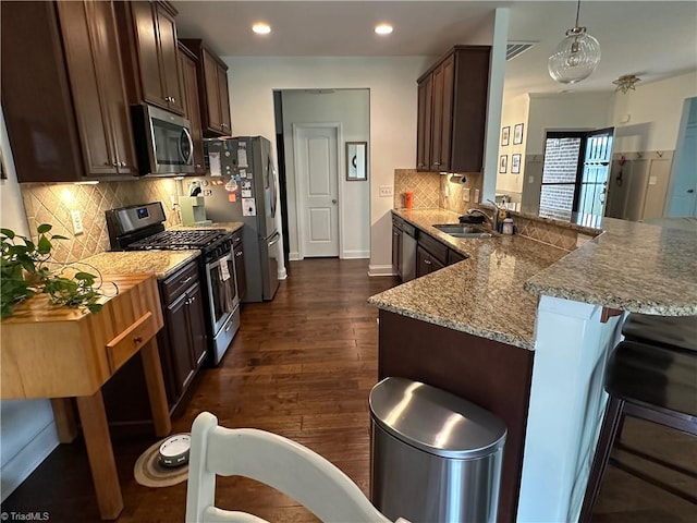 107 Saddlebrook Dr, Advance, NC 27006 - kitchen with stainless steel appliances, a peninsula, dark brown cabinetry, a kitchen breakfast bar, and dark wood finished floors