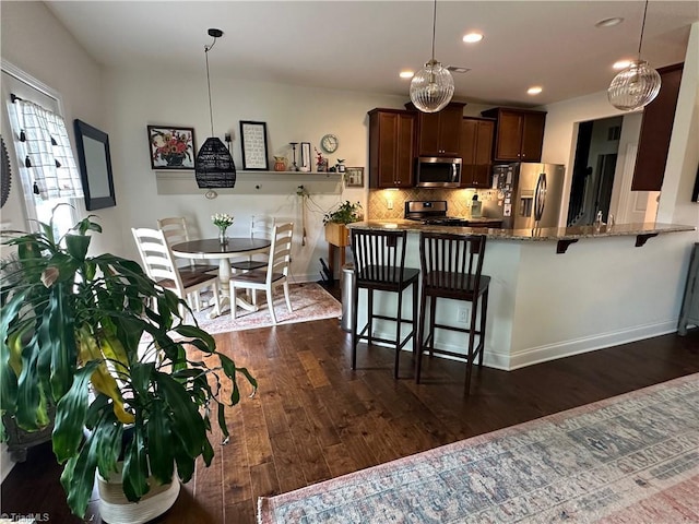 107 Saddlebrook Dr, Advance, NC 27006 - kitchen with appliances with stainless steel finishes, a kitchen bar, dark wood-type flooring, recessed lighting, and dark stone countertops