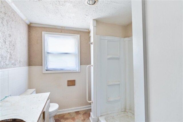 full bath featuring wainscoting, ornamental molding, walk in shower, a textured ceiling, and vanity