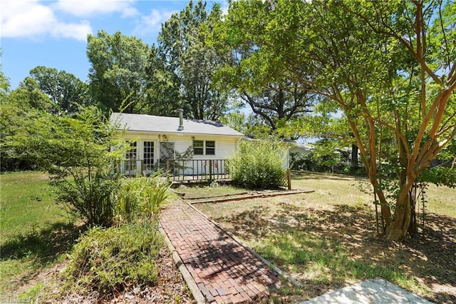 back of house featuring a deck, french doors, and a lawn