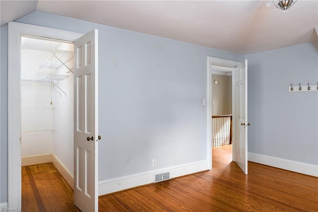 unfurnished bedroom featuring wood-type flooring, vaulted ceiling, and a closet