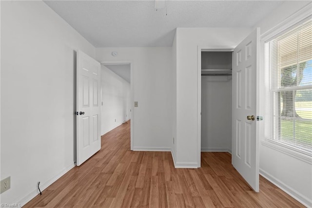 3785 Ellisboro Rd, Stokesdale, NC 27357 - unfurnished bedroom featuring light wood finished floors, multiple windows, baseboards, a closet, and a textured ceiling