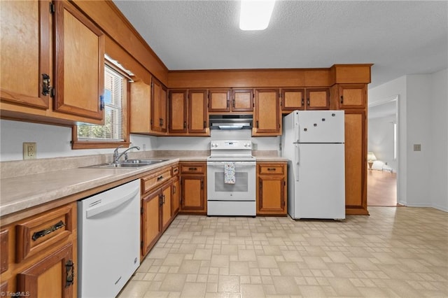 3785 Ellisboro Rd, Stokesdale, NC 27357 - kitchen with white appliances, under cabinet range hood, brown cabinets, a sink, and light countertops