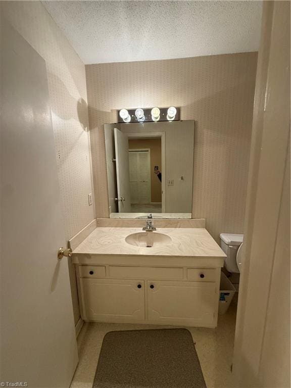 bathroom featuring vanity, a textured ceiling, and toilet