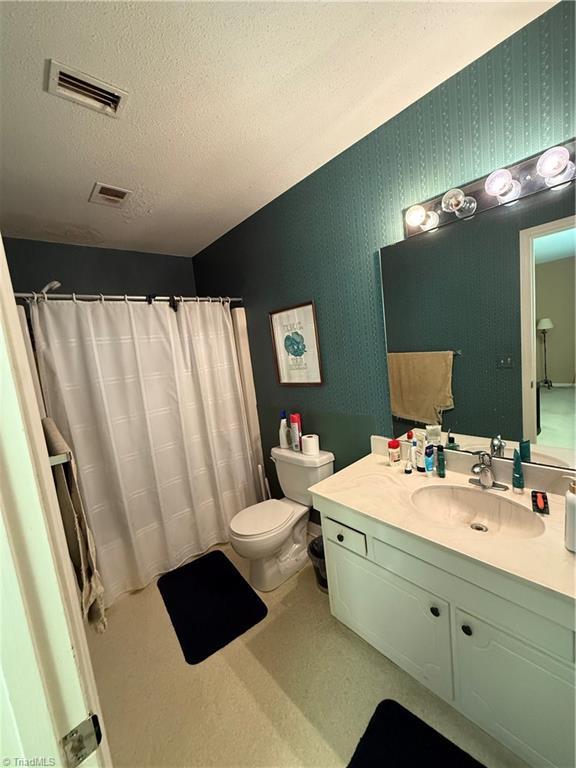 bathroom with vanity, toilet, and a textured ceiling