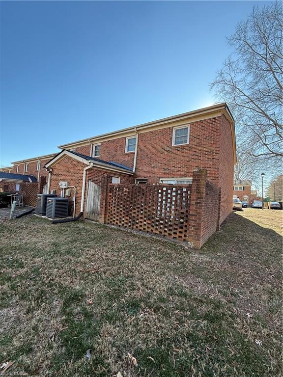 rear view of house with a lawn and central AC