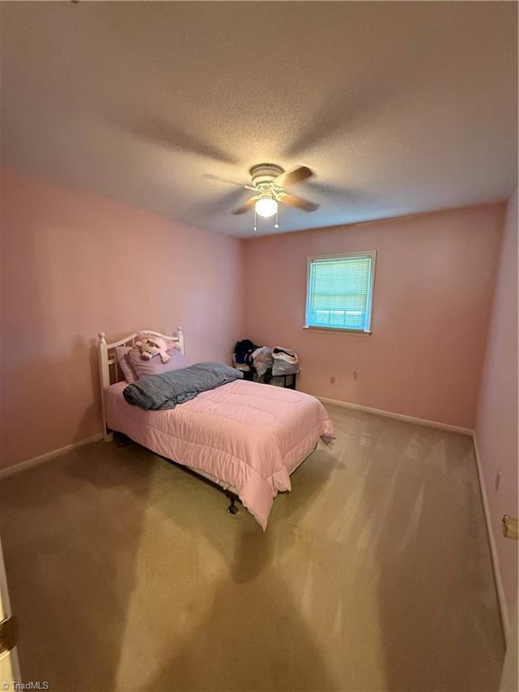 carpeted bedroom featuring ceiling fan and a textured ceiling