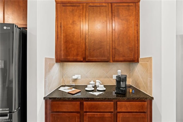1720 Ridge Bluff Cir, Rural Hall, NC 27045 - kitchen with freestanding refrigerator, decorative backsplash, dark stone counters, and brown cabinetry