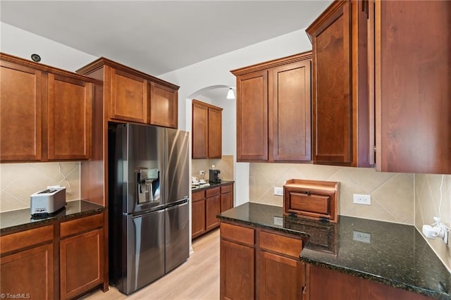 1720 Ridge Bluff Cir, Rural Hall, NC 27045 - kitchen featuring stainless steel refrigerator with ice dispenser, arched walkways, decorative backsplash, dark stone countertops, and light wood finished floors