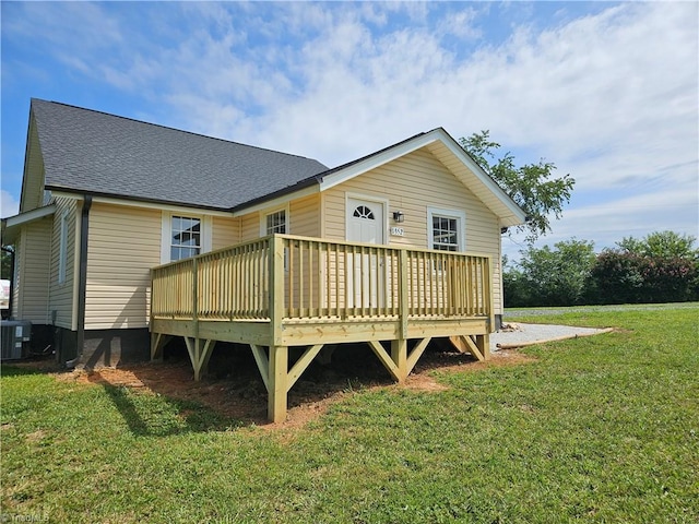 back of property with central AC, a lawn, a wooden deck, and roof with shingles