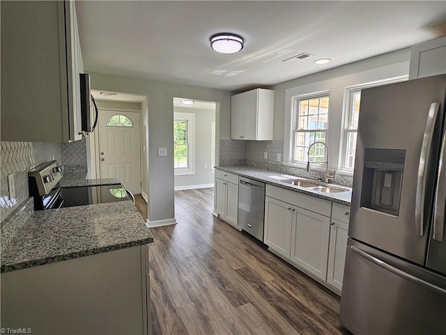 kitchen with stone countertops, visible vents, stainless steel appliances, and a sink