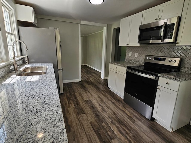 kitchen with stainless steel appliances, dark wood finished floors, light stone counters, and decorative backsplash