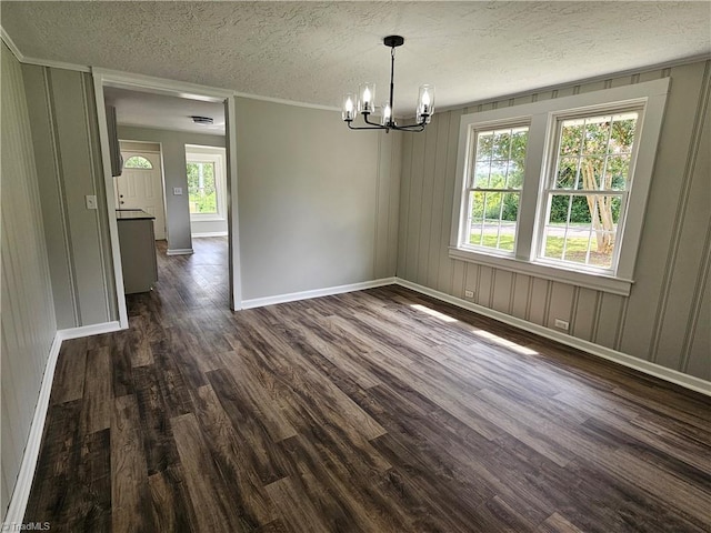 unfurnished dining area with a textured ceiling, dark wood-type flooring, plenty of natural light, and a notable chandelier