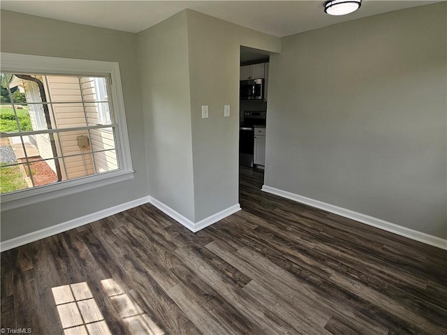 unfurnished room with dark wood finished floors and baseboards