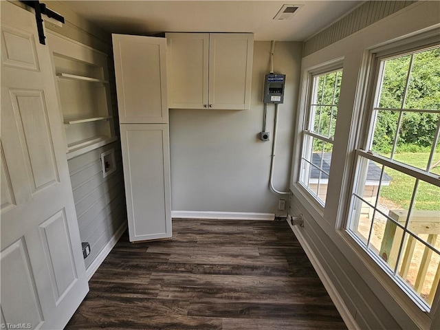 interior space featuring laundry area, a barn door, baseboards, visible vents, and dark wood-type flooring