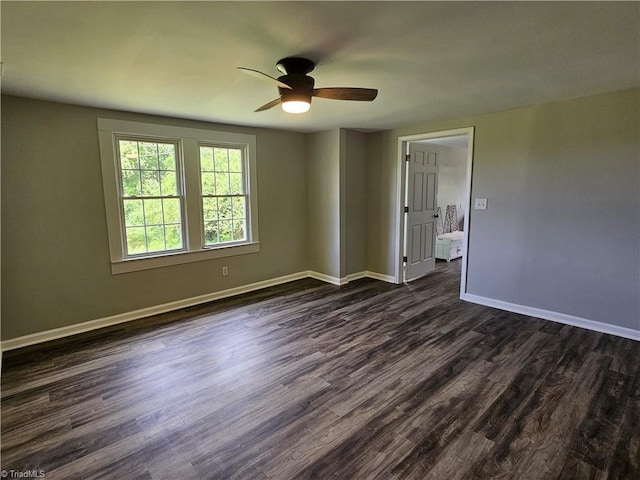 empty room featuring a ceiling fan, dark wood finished floors, and baseboards