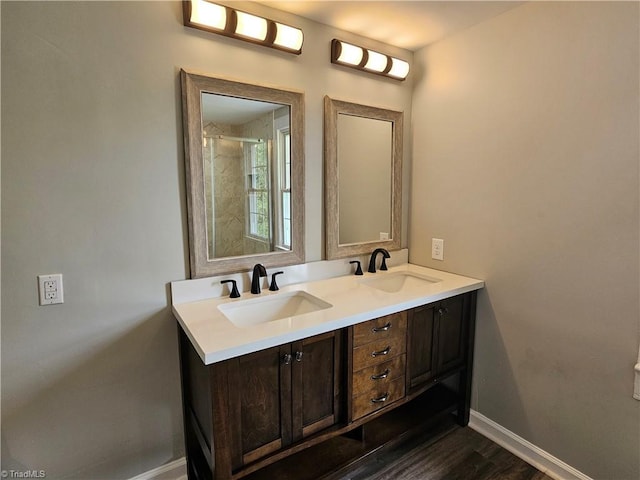 full bathroom featuring wood finished floors, a sink, baseboards, and double vanity