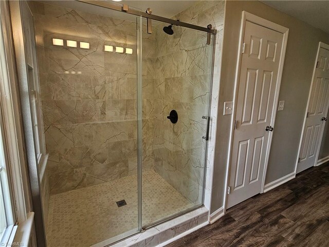 full bathroom featuring a stall shower, wood finished floors, and baseboards