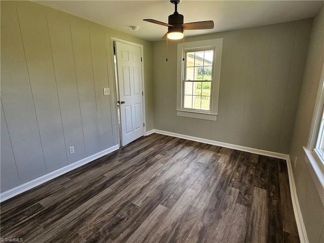 spare room featuring a ceiling fan, dark wood-style flooring, and baseboards