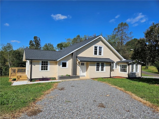 view of front of house with a deck, a front lawn, and a shingled roof