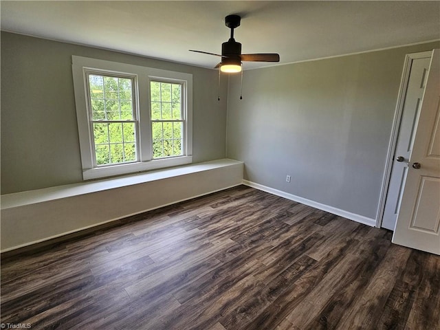 spare room with ceiling fan, dark wood-type flooring, and baseboards