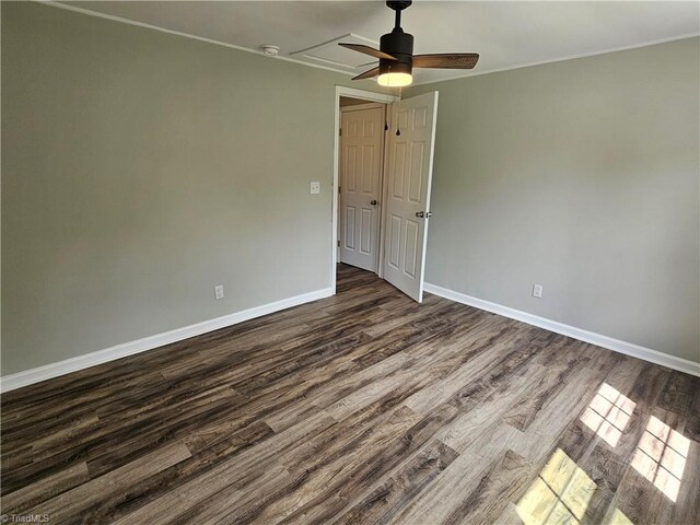 spare room with dark wood-style floors, crown molding, baseboards, and a ceiling fan