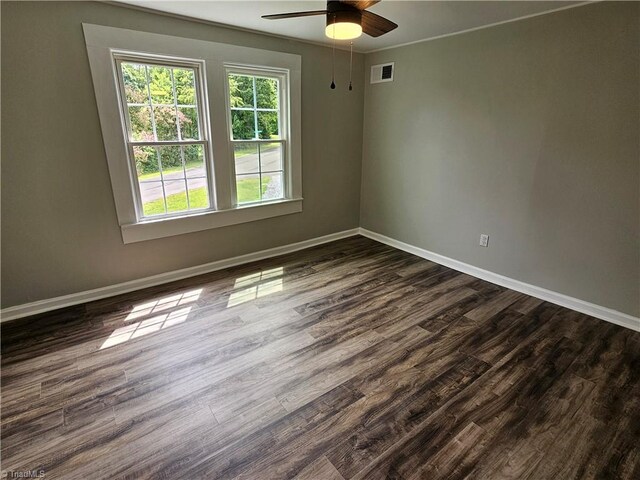 empty room featuring baseboards, visible vents, and dark wood-type flooring