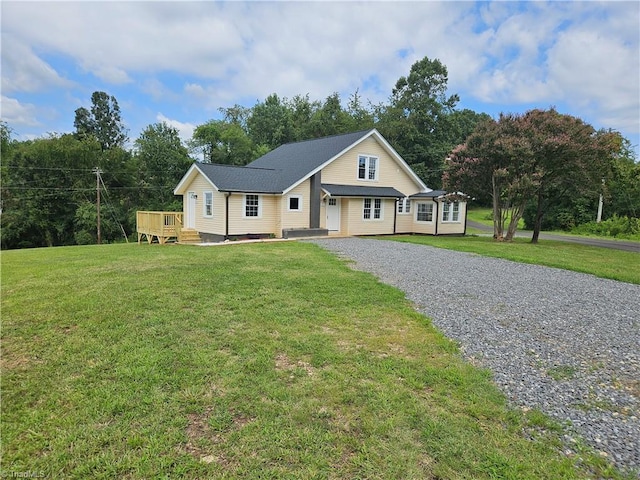 view of front of house with driveway, a wooden deck, and a front yard