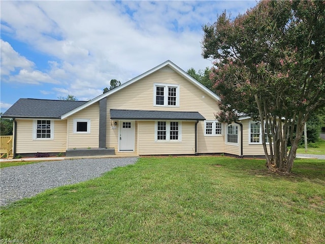 view of front of house with roof with shingles and a front yard