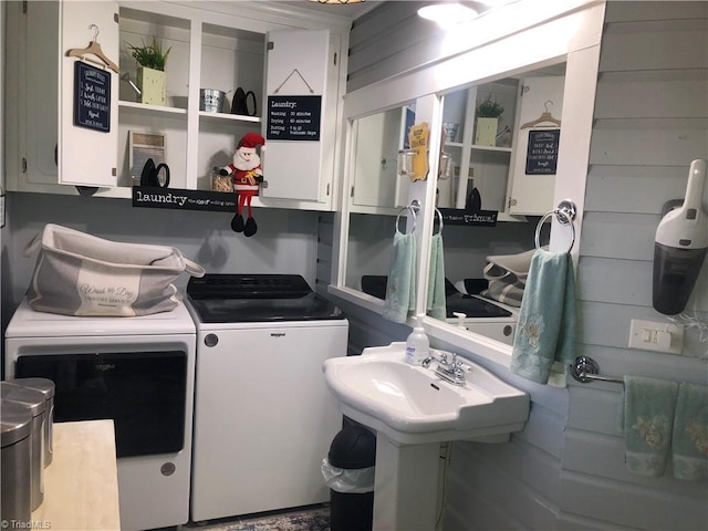 laundry area with cabinets, wooden walls, and washing machine and clothes dryer