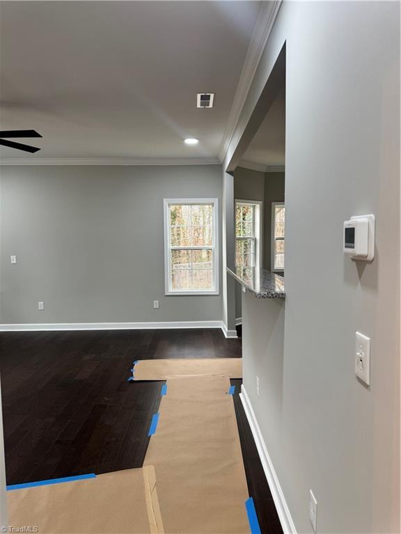 interior space featuring dark hardwood / wood-style flooring, ornamental molding, and ceiling fan