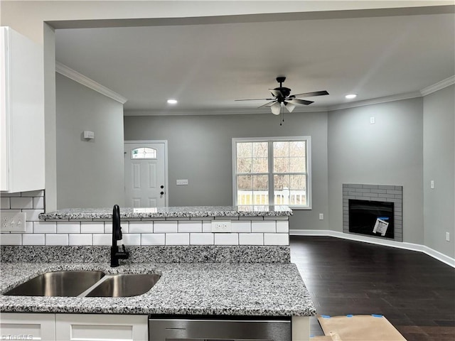 kitchen with light stone counters, sink, a fireplace, and white cabinets